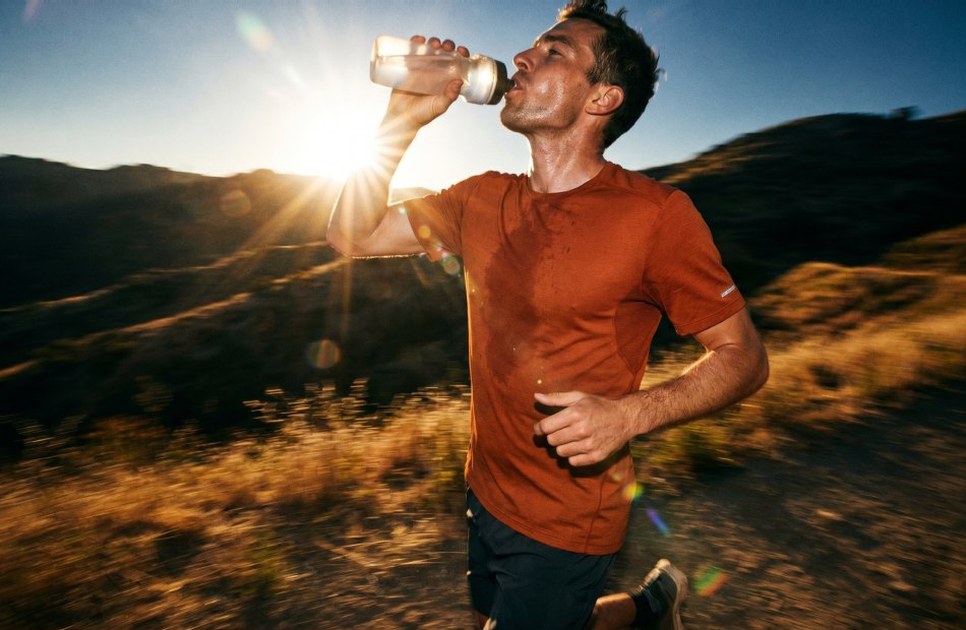 A runner drinking on a mountain trail, shot in motion